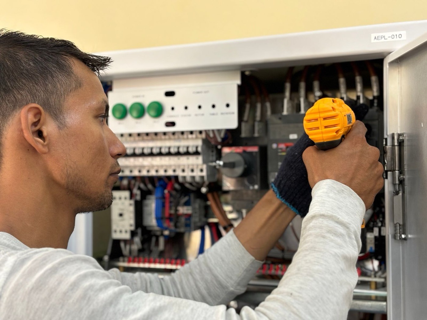 Electrician working with a drill while mounting electrical equipment